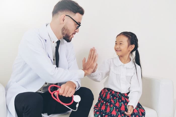 Kings College Doctor high fiving patient Family Doctor with little girl patient